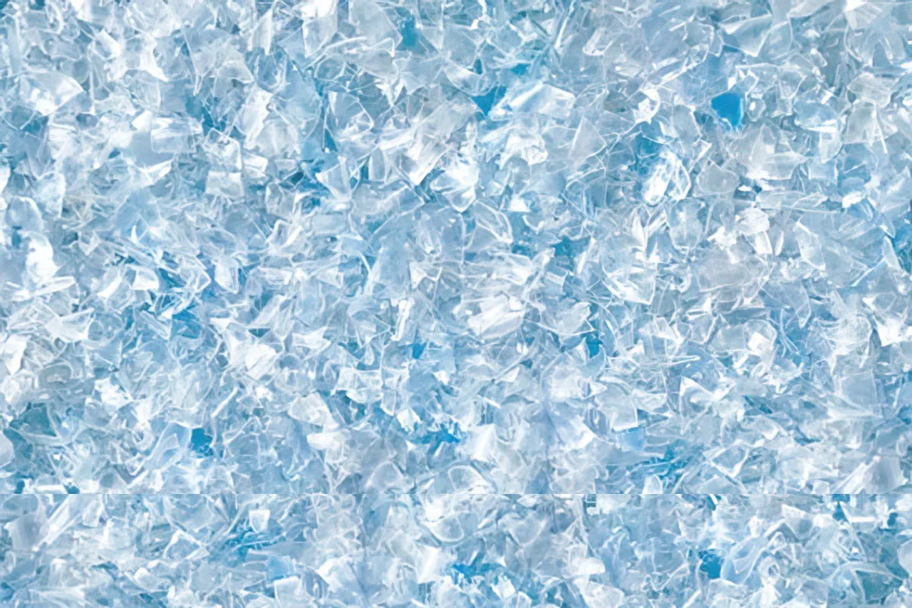 Close-up view of many small, irregularly shaped, translucent plastic flakes with a light blue tint, densely spread across the image—ideal for use beneath Stilj™ Sustainable Acoustic Wood Paneling.